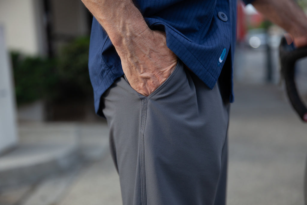 A model showing the front slash pocket of the TRANSVERSE downtown trousers in grey