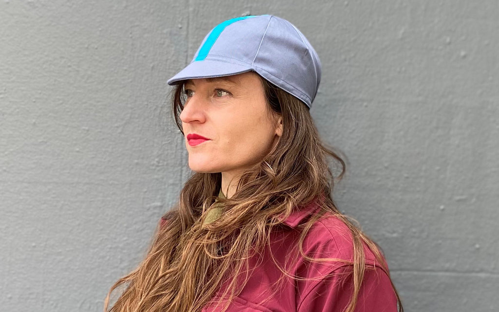 Muriel is wearing the 4-panel cotton cap in blue-grey with cyan ribbon